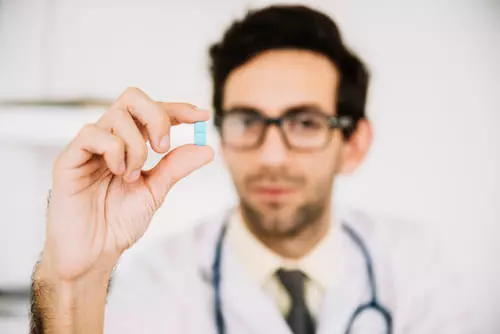 врач держит в руке таблетку от запоя 